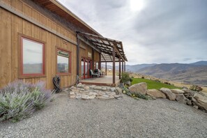 A wooden building with a covered porch, stone steps, and a gravel driveway.