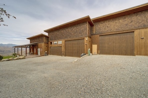 A two-story building with a gravel driveway and large wooden garage doors.