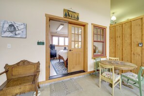 A room with a wooden door, a bed, a table with chairs, and a painting on the wall. - Hot Tub, Valley Views & 40 Acres in Methow (Pateros)