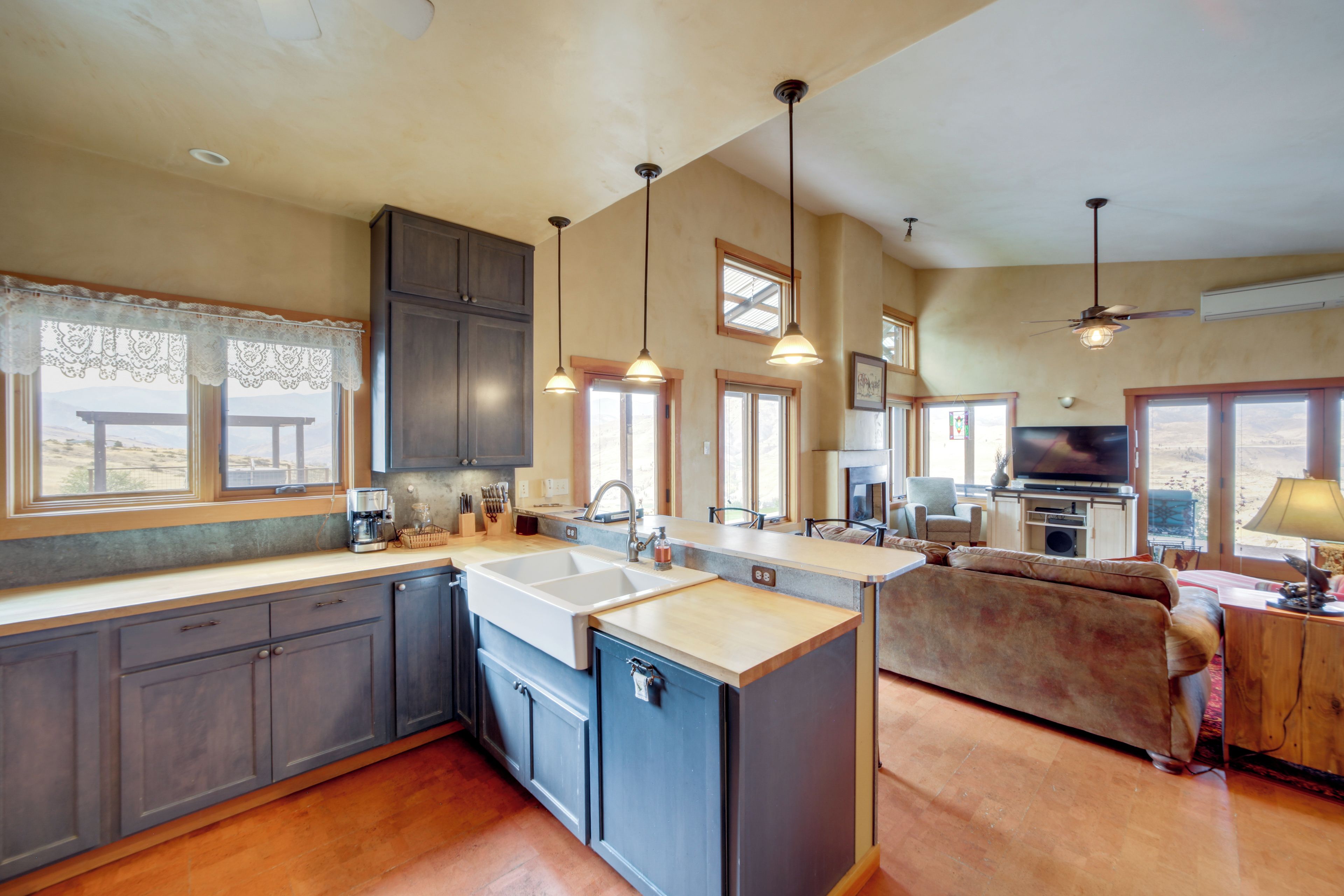 A spacious kitchen with a large island, dark cabinets, and pendant lighting.