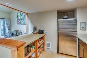 A modern kitchen with a wooden countertop, stainless steel refrigerator, and a dining area with a glass table and chairs. - Walk to Ski Slopes! Sun Valley Condo w/ Balcony (Ketchum)