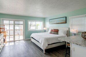 Un dormitorio con cama, cómoda, ventana con persianas y vistas al exterior.