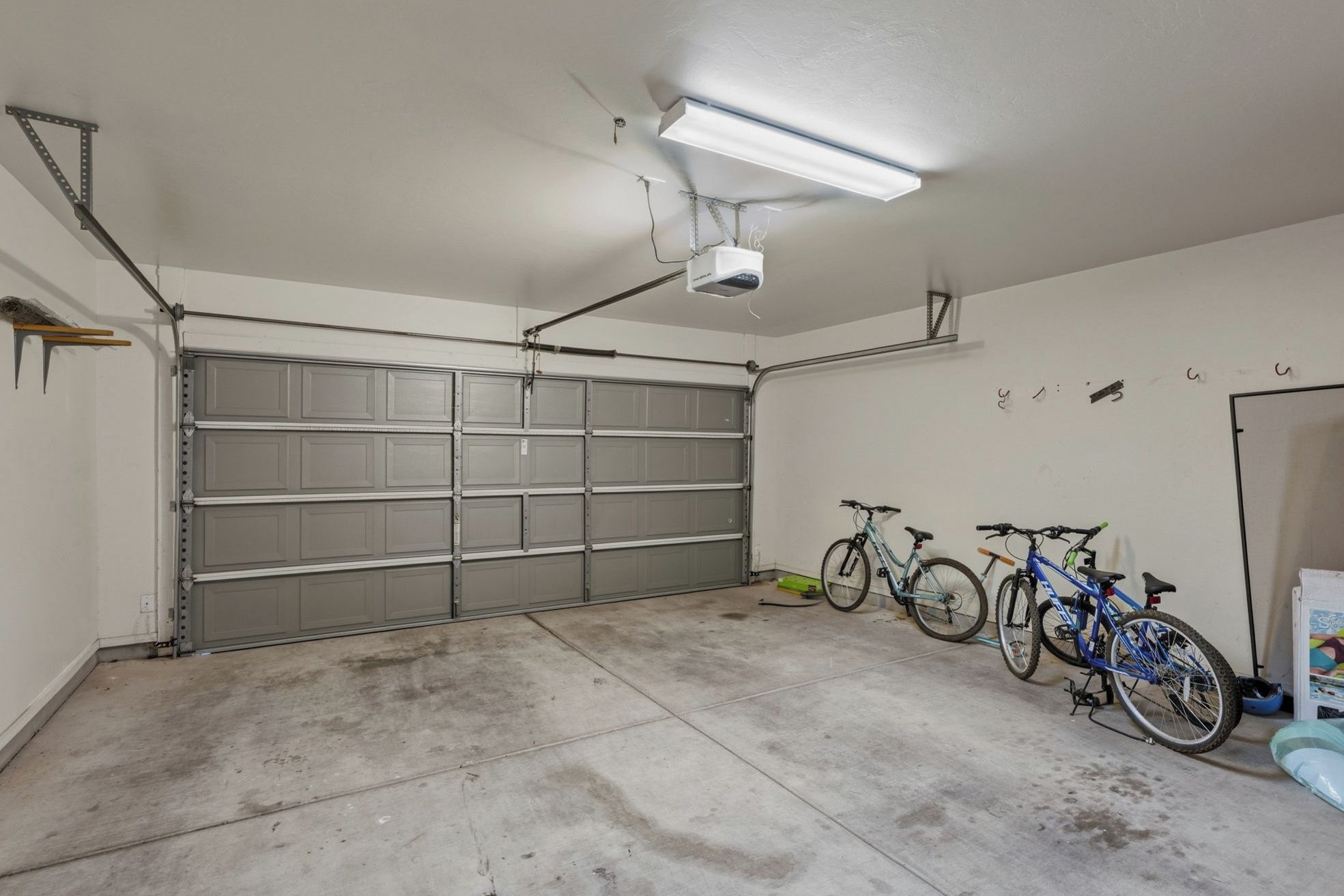 Een garage met een grote overheadlamp, een gesloten garagepoort en twee fietsen erin.