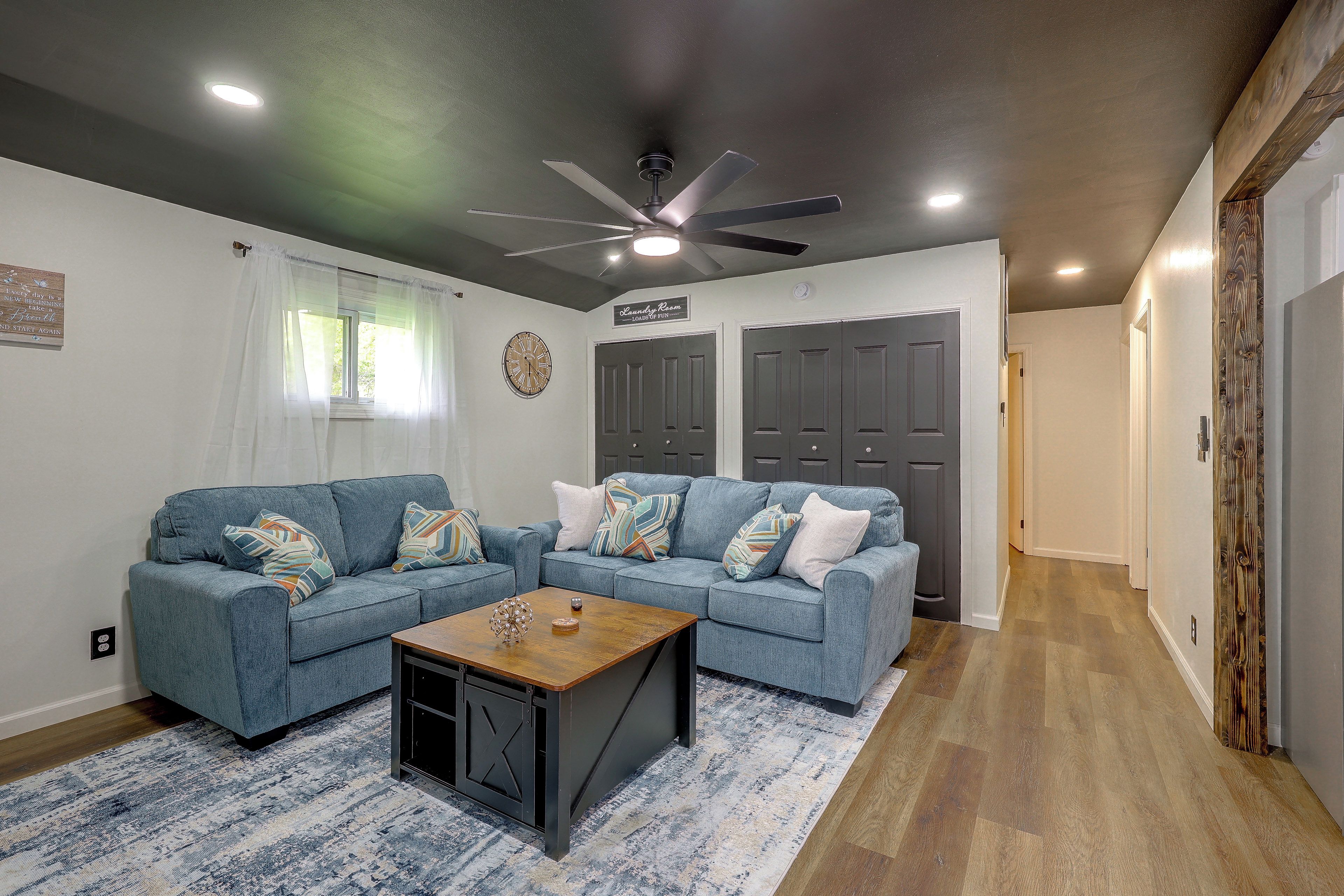 A living room with two sofas, a coffee table, and a ceiling fan.