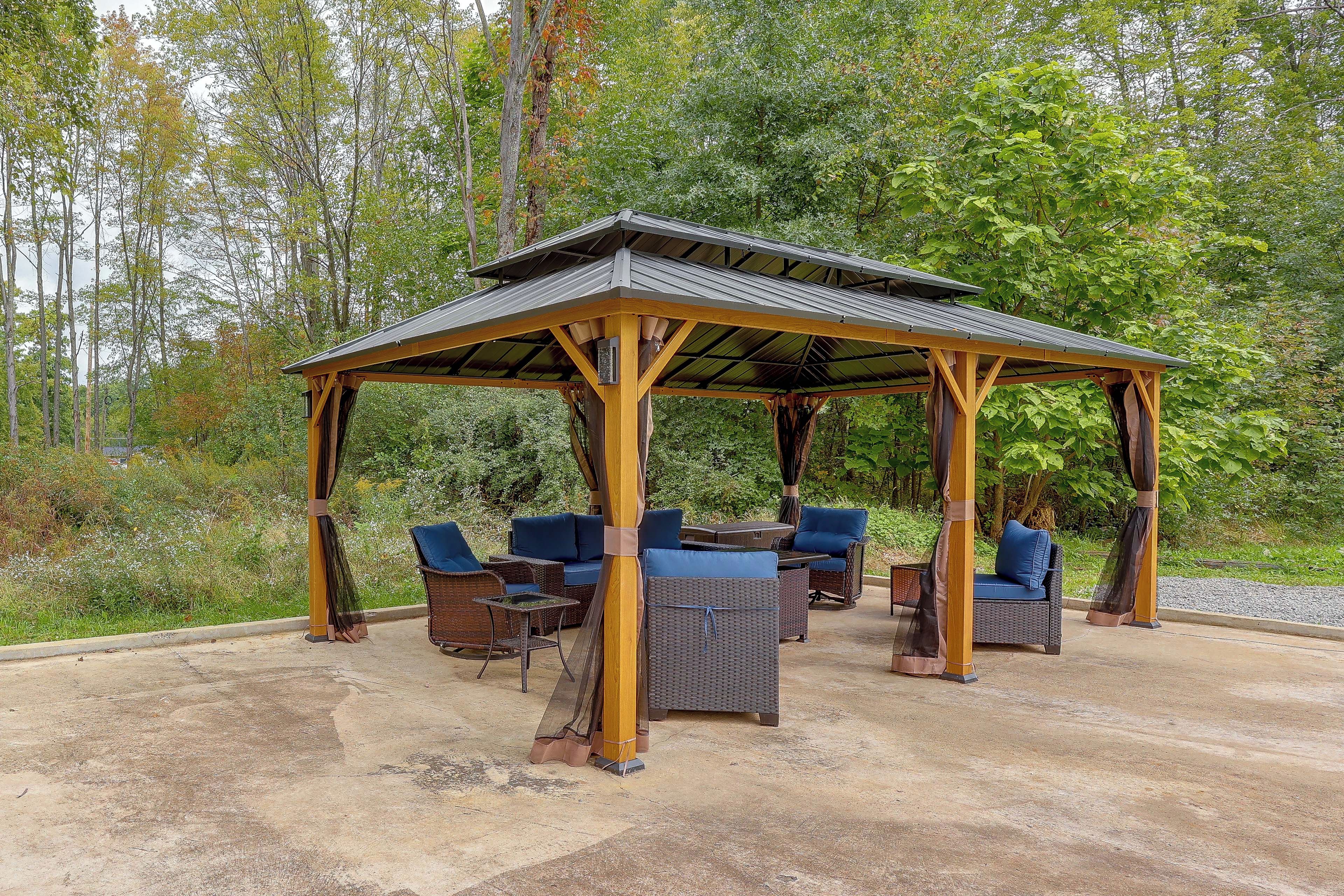 Een overdekt terras met rieten meubels en blauwe kussens.