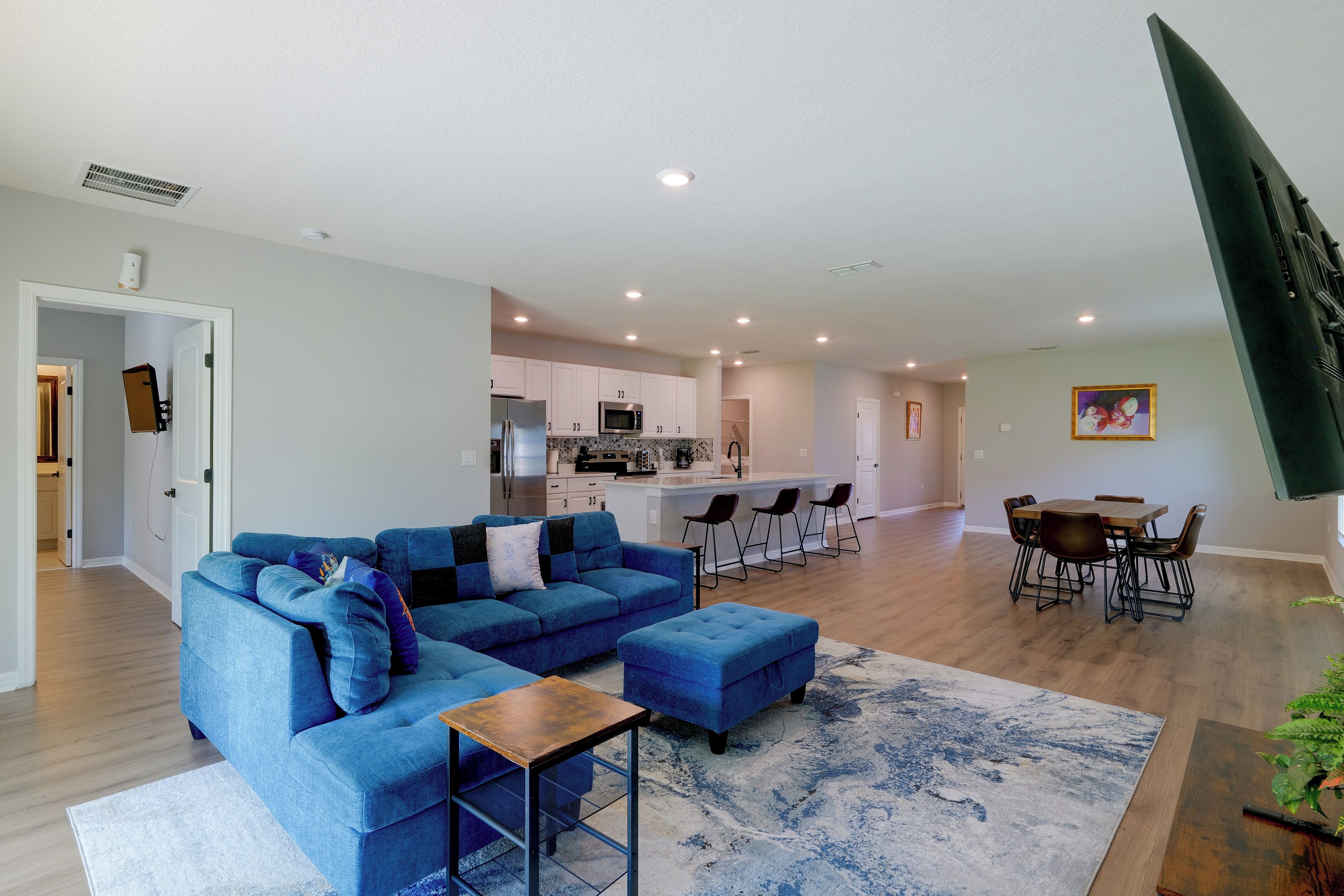 A modern living room with a sectional sofa, a coffee table, and a dining area with a wooden table and chairs.