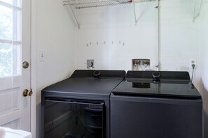 A laundry room with two front-loading washers and dryers, a window, and a door. - Dayton Area Extended Stay w/ Half-acre Garden (Dayton)