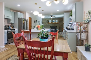 A modern kitchen with a dining area, wooden chairs, a central island, and a built-in oven.