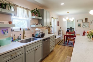 Una cocina moderna con lavavajillas, pileta y comedor con una silla roja y una mesa.