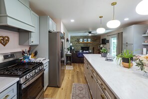 A modern kitchen with a central island, stainless steel appliances, and a stone fireplace.