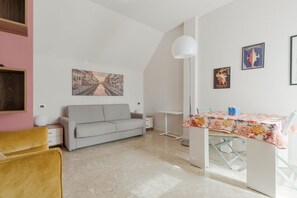 Una habitació amb un sofà, una taula de menjador amb estovell floral i un quadre a la paret.