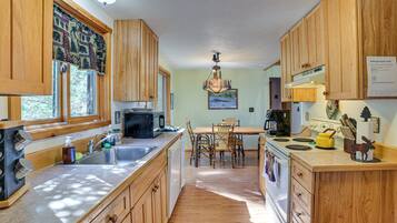A kitchen with wooden cabinets, a microwave, a sink, and a dining area with chairs.