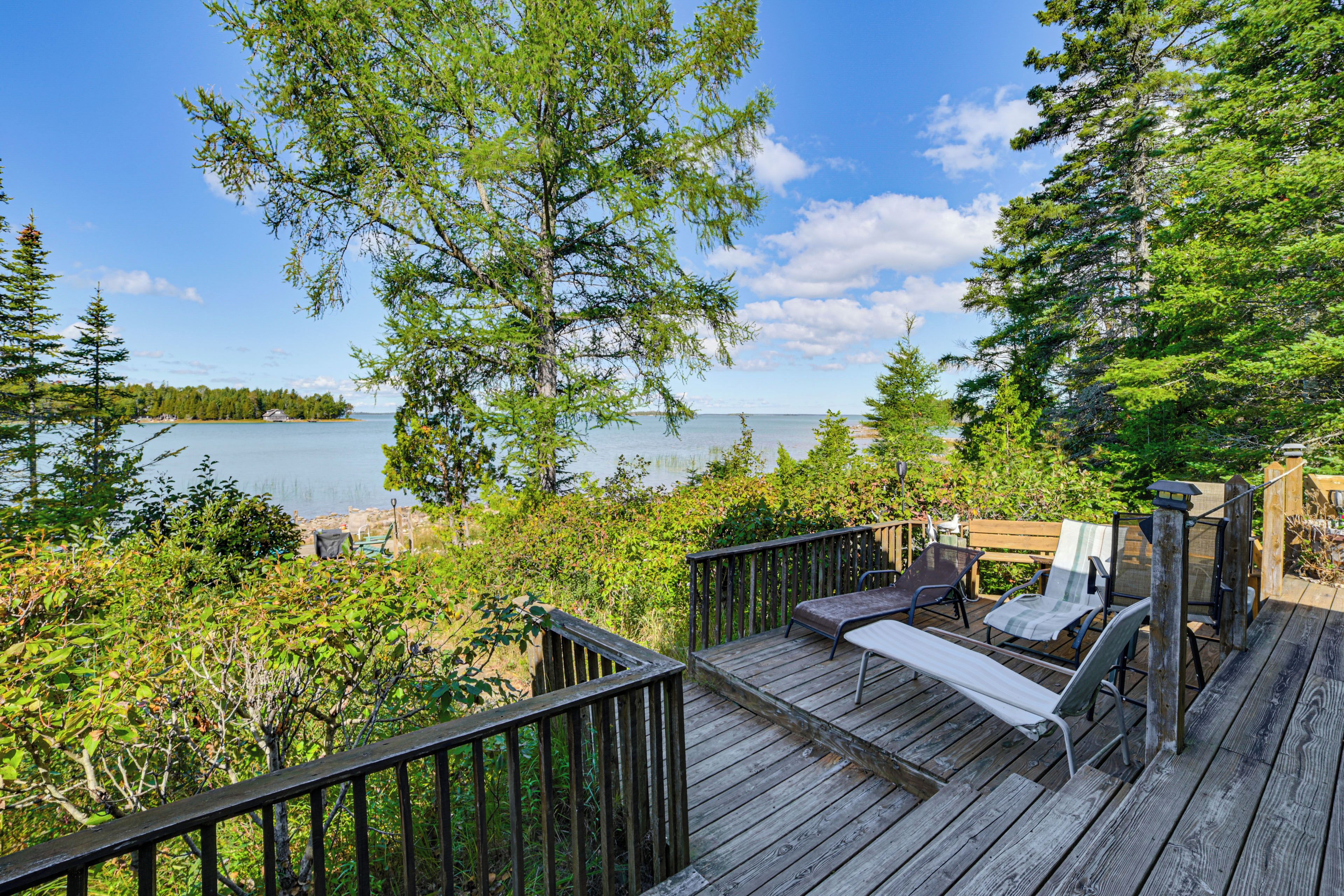 A wooden deck with outdoor furniture overlooking a lake.
