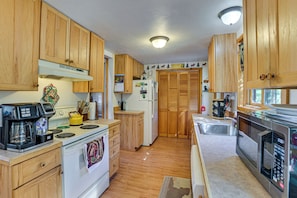 Una cocina con gabinetes de madera, estufa, cafetera y microondas.