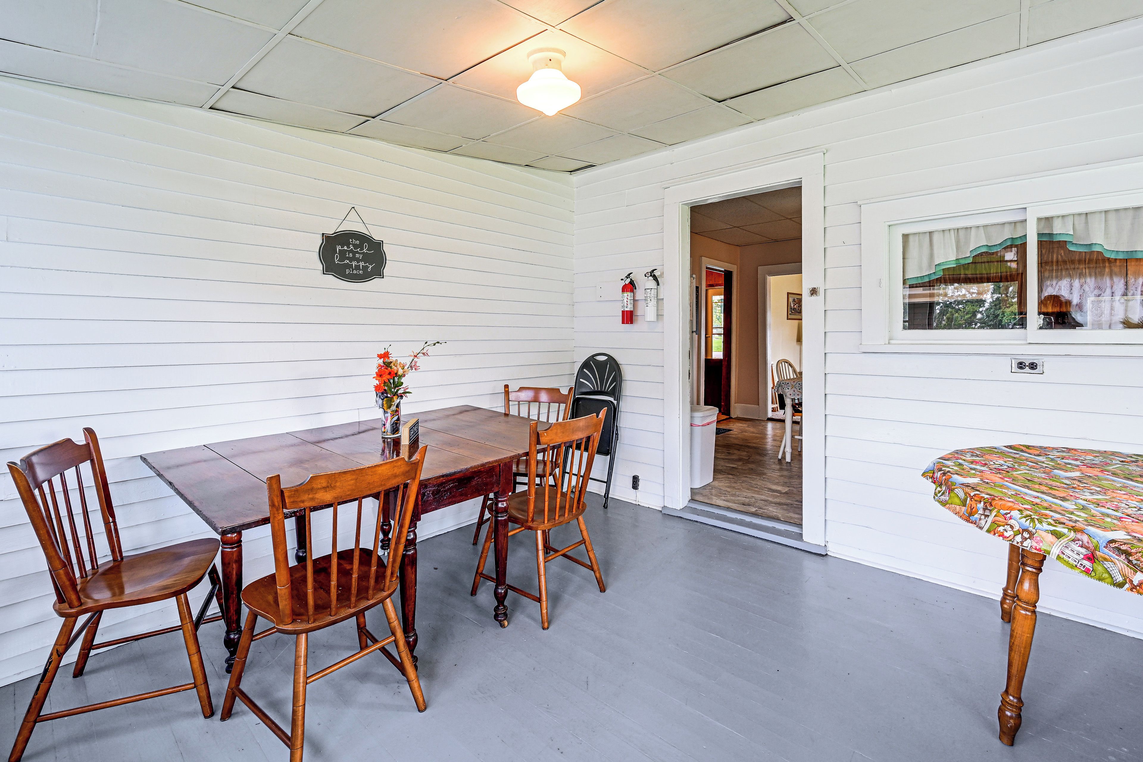 A dining area with a wooden table and chairs, a vase with flowers, and a wall-mounted sign.