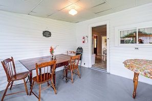 A dining area with a wooden table and chairs, a vase with flowers, and a wall-mounted sign.