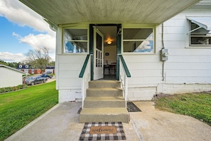A house with a front porch, a set of stairs leading to the entrance, and a doormat with the word 'welcome'.