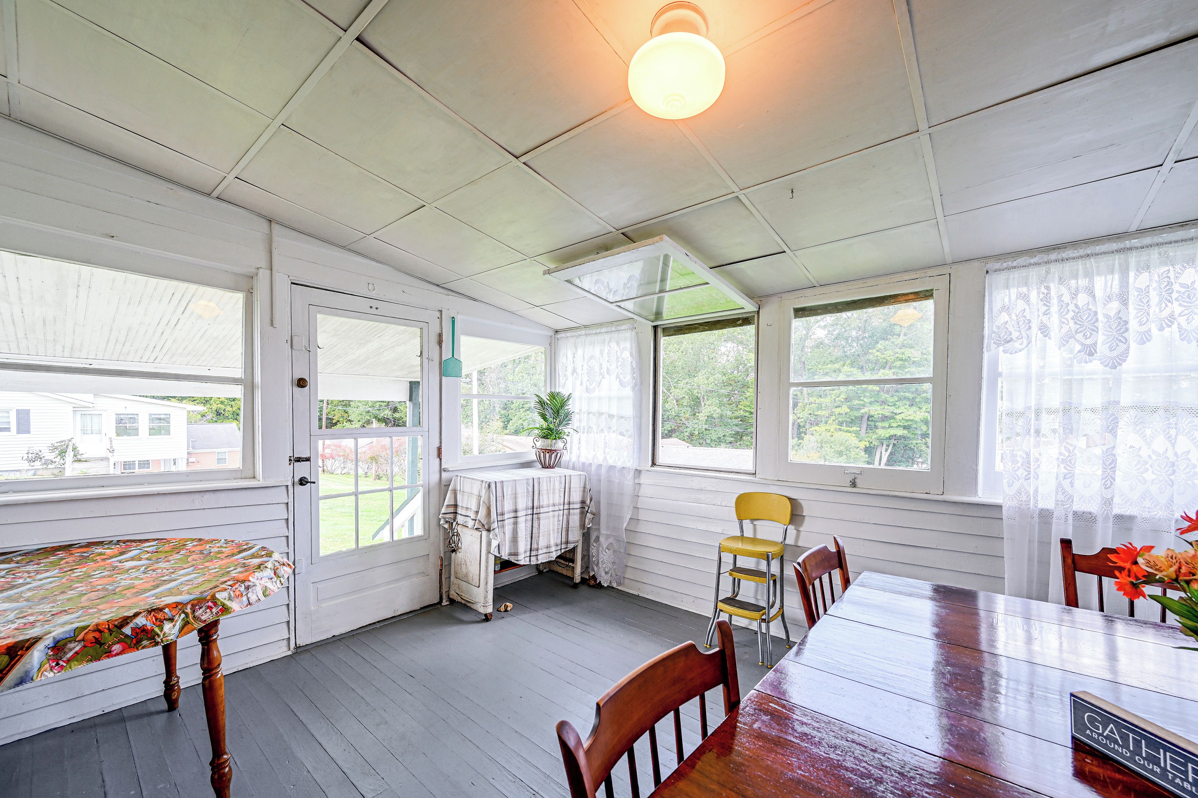 A sunroom with a table and chairs, a ceiling fan, and large windows.