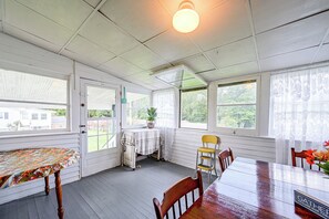 A sunroom with a table and chairs, a ceiling fan, and large windows. - 1 Mi to Downtown! Cute Cambridge Getaway (Cambridge)