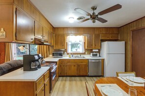 A compact kitchen with wooden cabinets, a microwave, a toaster, and a refrigerator.