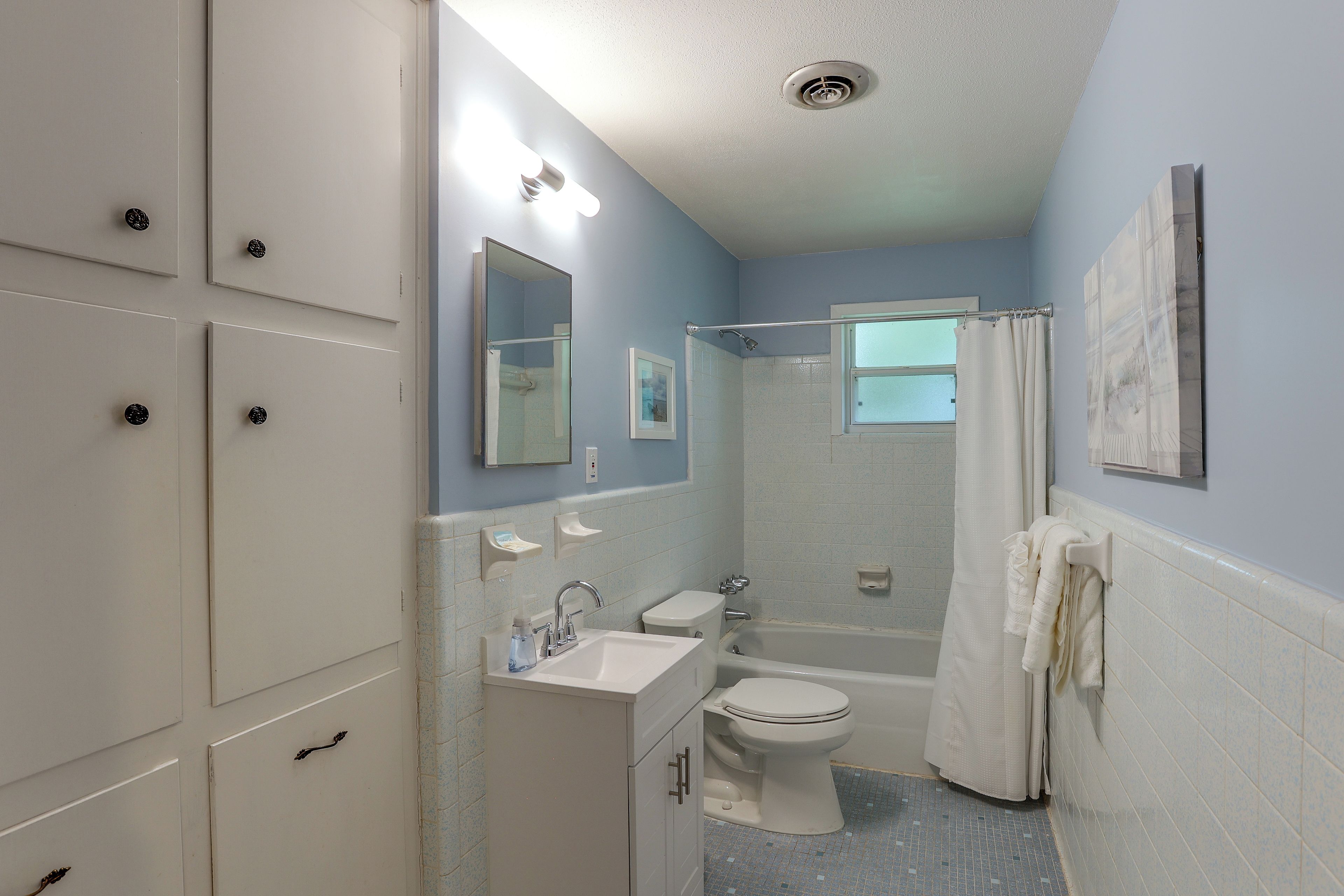 A bathroom with a shower, toilet, sink, and a towel rack.
