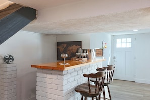 A bar area with a wooden counter, white brick base, and wooden bar stools.