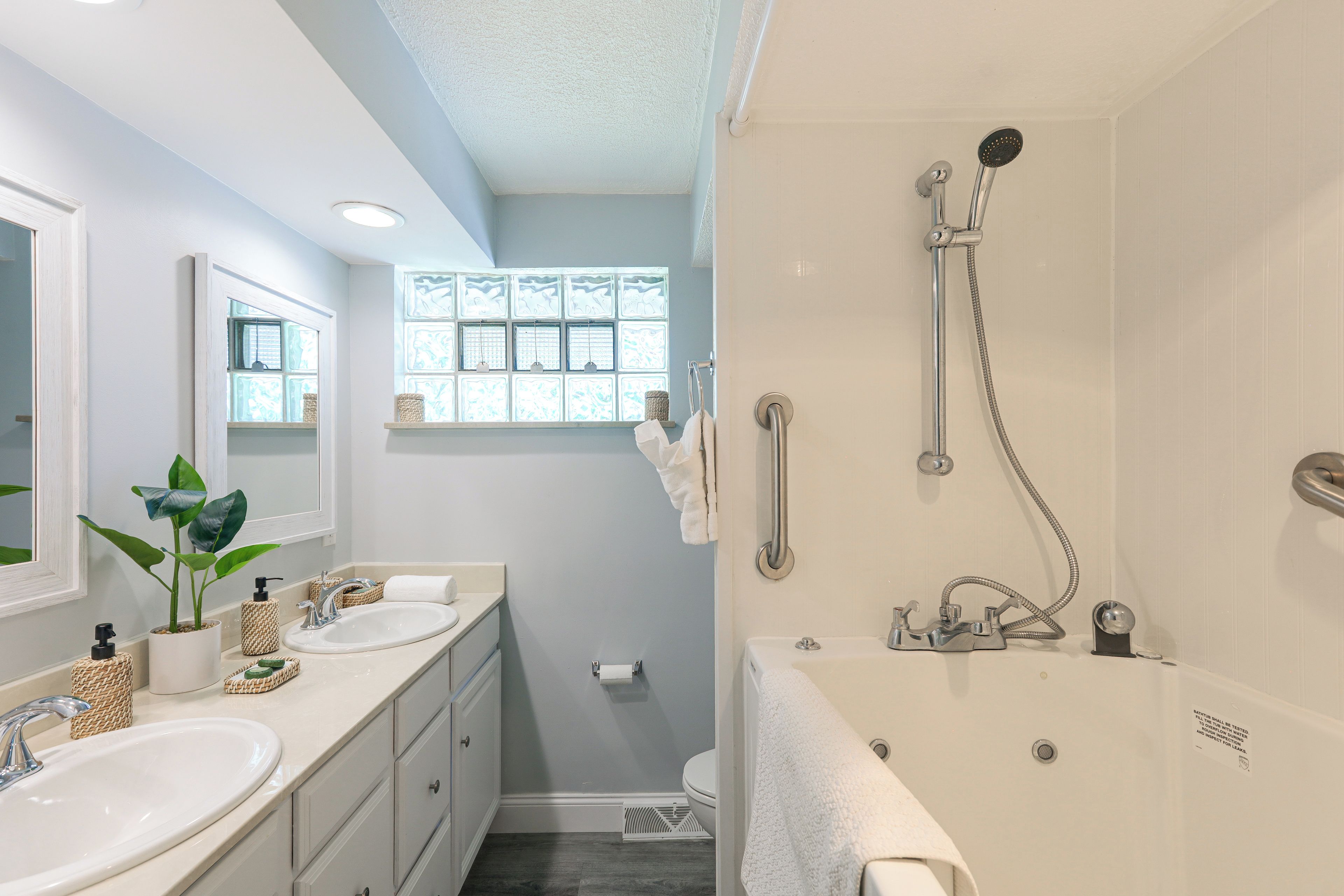 A bathroom with two sinks, a shower, a window with a view, and a towel rack.
