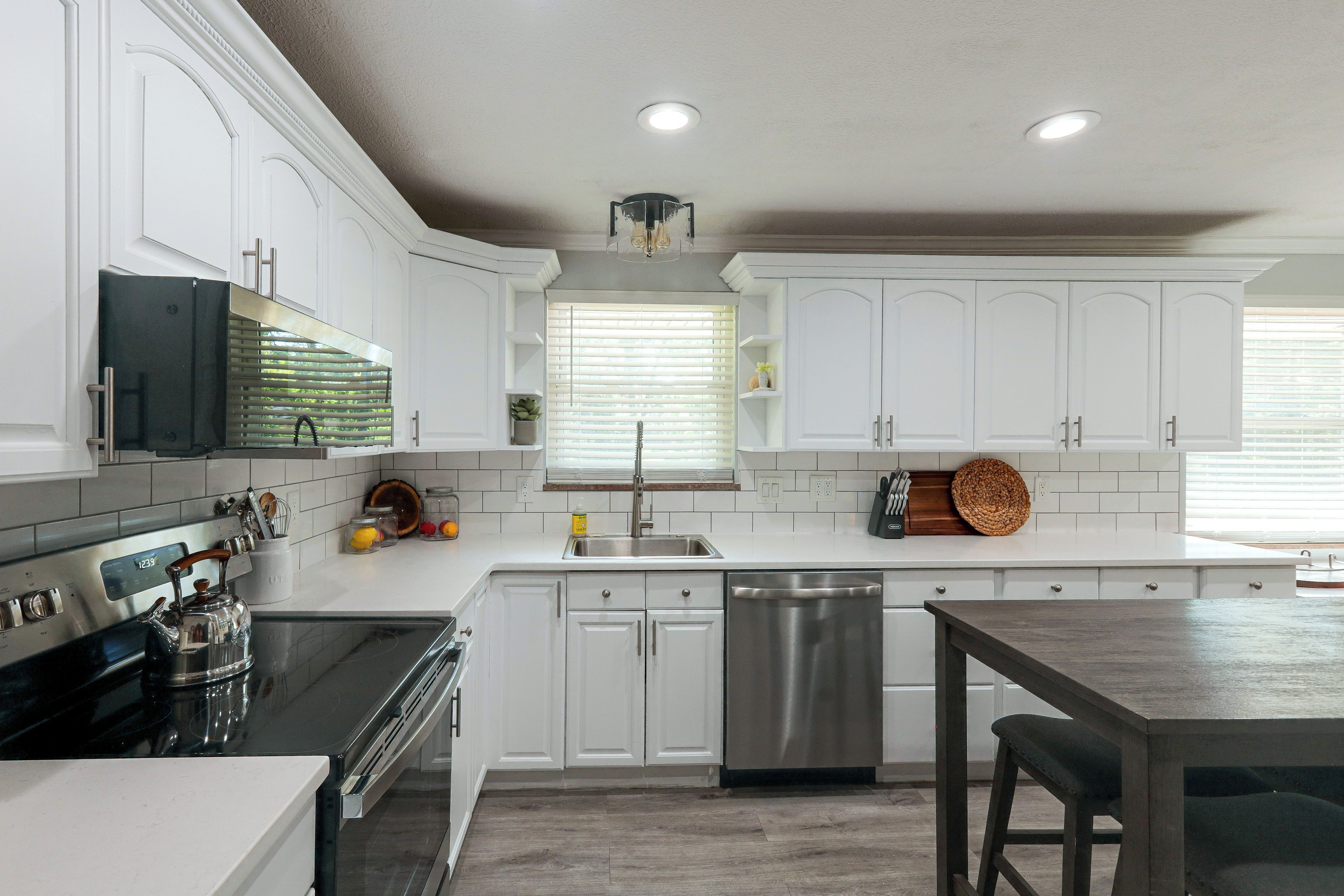 A modern kitchen with white cabinetry, stainless steel appliances, and a central island.