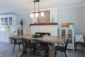 A dining area with a large wooden table, black chairs, and a white brick fireplace. - Outdoor Oasis w/ Hot Tub & Pool! Milford Gem (Milford)