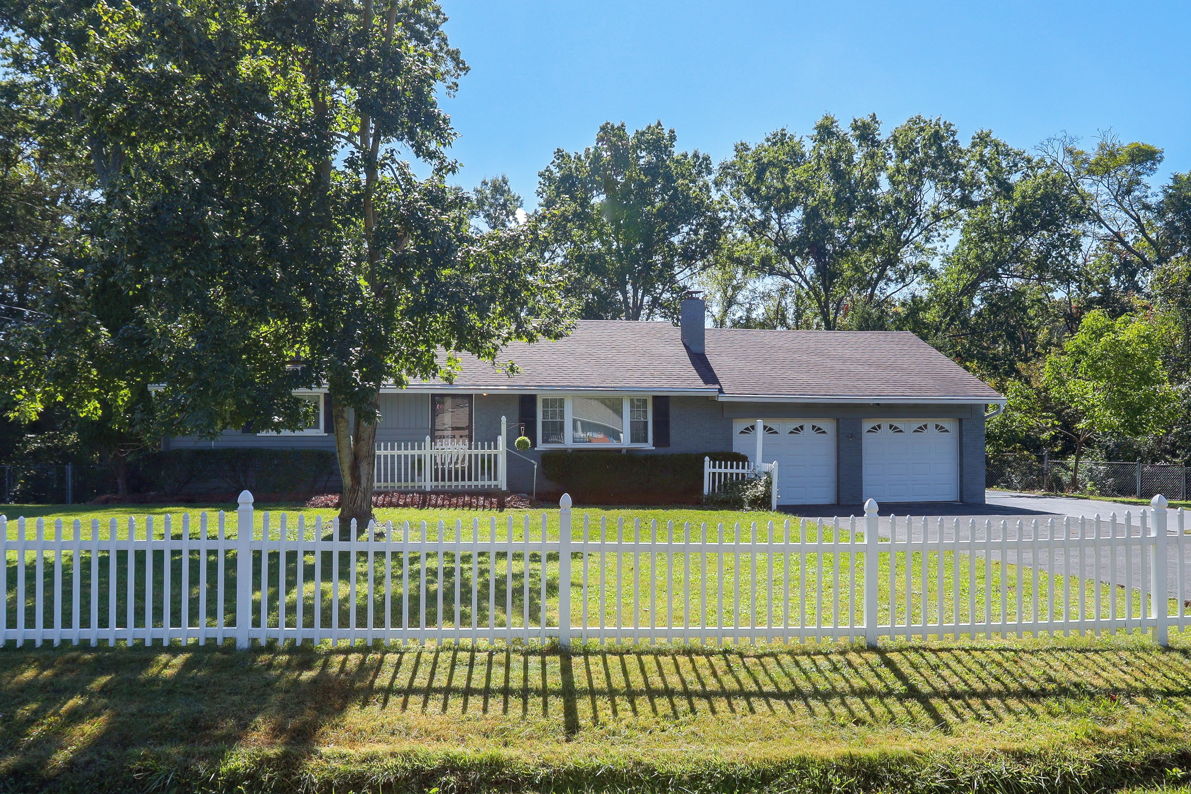 A residential house with a white picket fence, a garage, and a lawn.