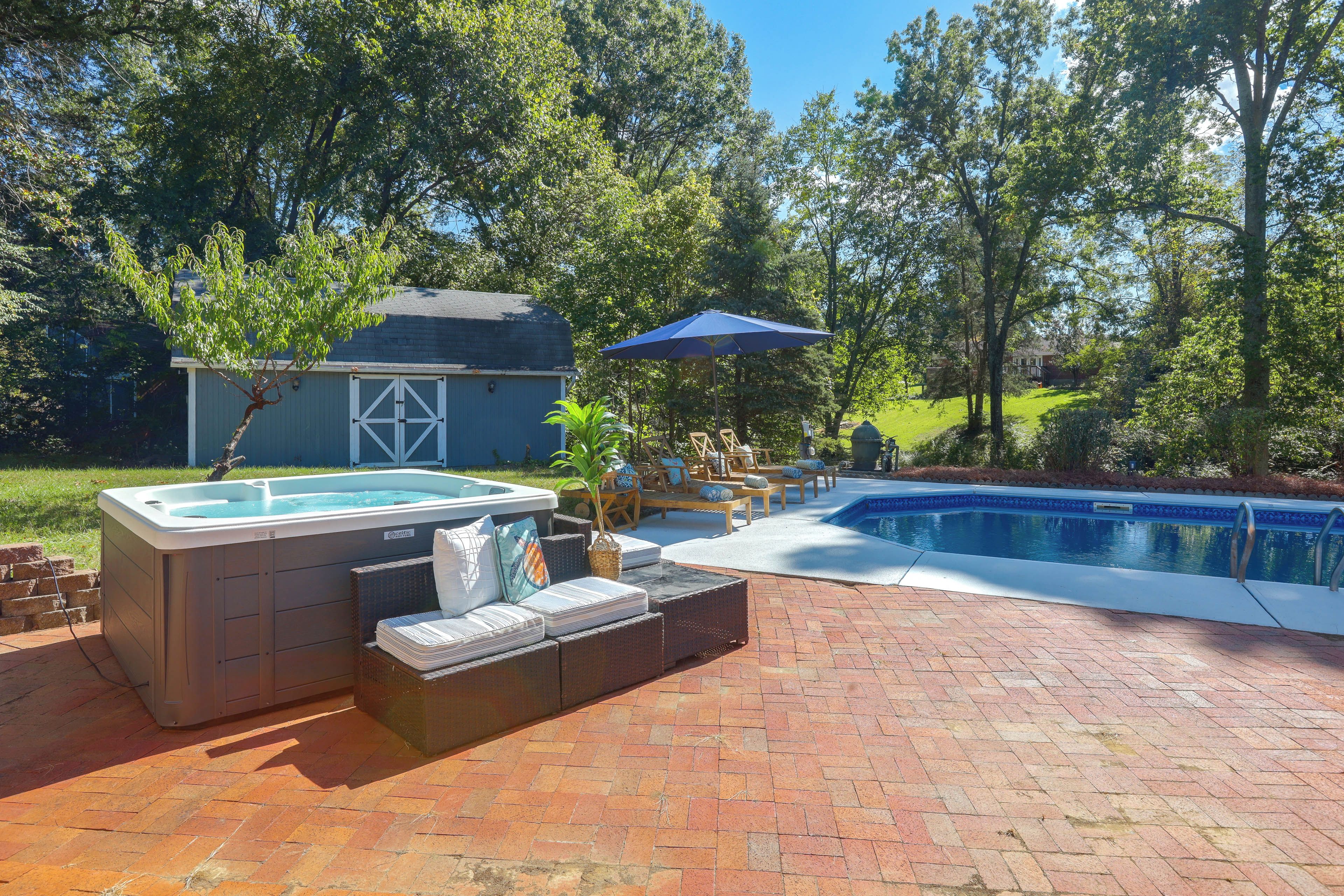 A backyard with a hot tub, a pool, and outdoor seating.