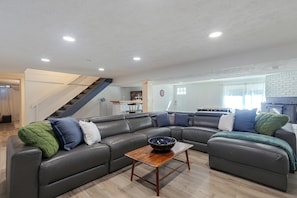 Una sala de estar moderna con un sofá modular, una mesa de centro de madera y una escalera que lleva a un nivel superior.