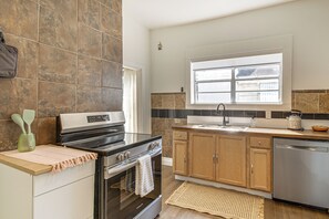 Cozinha moderna com forno embutido, lava-louças de aço inoxidável e armários de madeira.