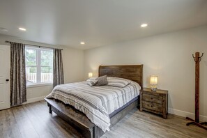 A bedroom with a bed, bedside lamps, a wooden bench, and a coat rack. - Hot Tub & Fenced Yard! Family Escape in Lancaster (Lancaster)