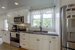 A modern kitchen with white cabinetry, stainless steel appliances, a built-in microwave, and a window with a view of greenery. - Hot Tub & Fenced Yard! Family Escape in Lancaster (Lancaster)