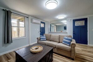 Una sala de estar con un sofá, una mesa de centro y una ventana con cortinas.