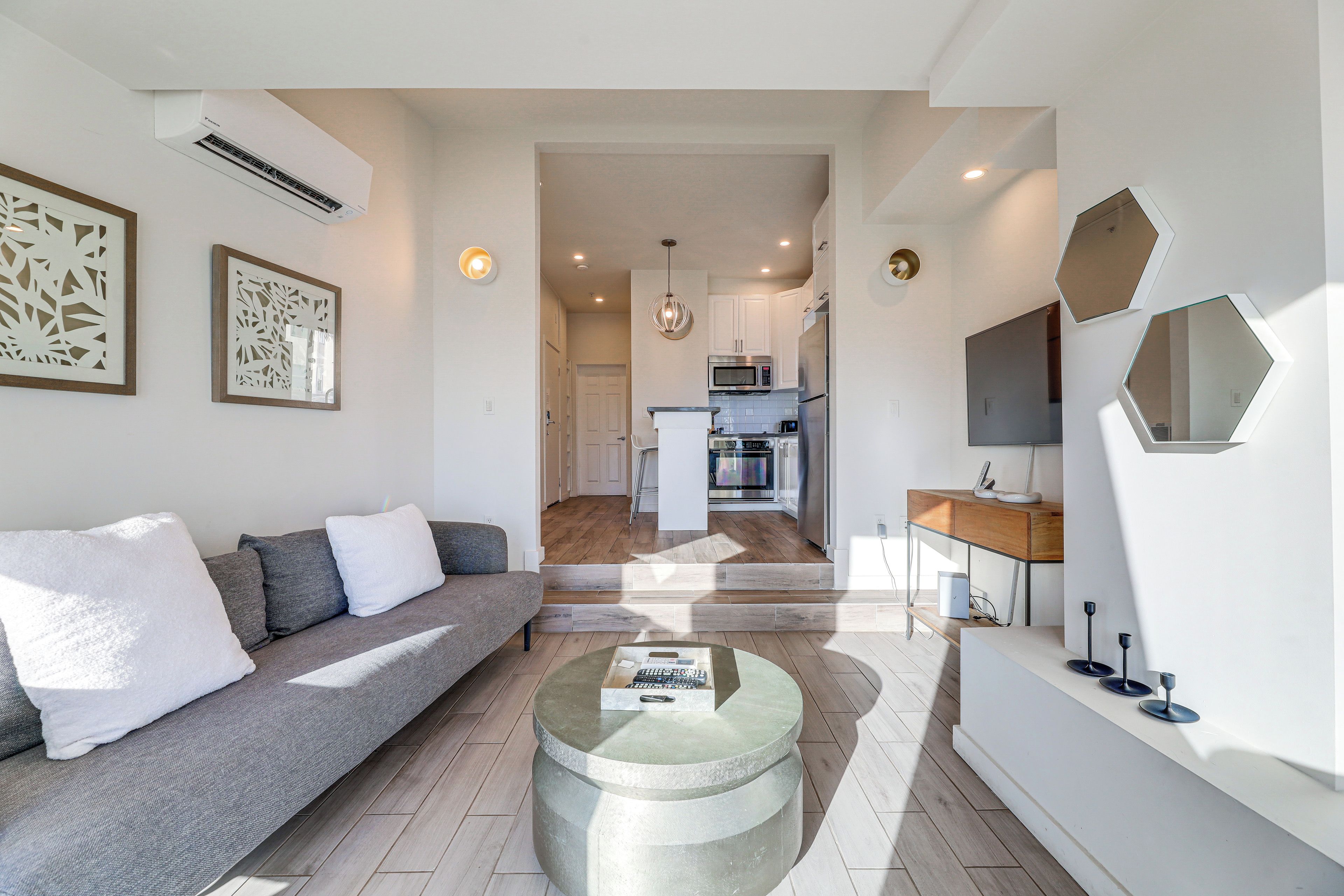A modern living room with a grey sofa, a coffee table, and a kitchen in the background.