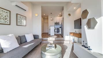 A modern living room with a grey sofa, a coffee table, and a kitchen in the background.