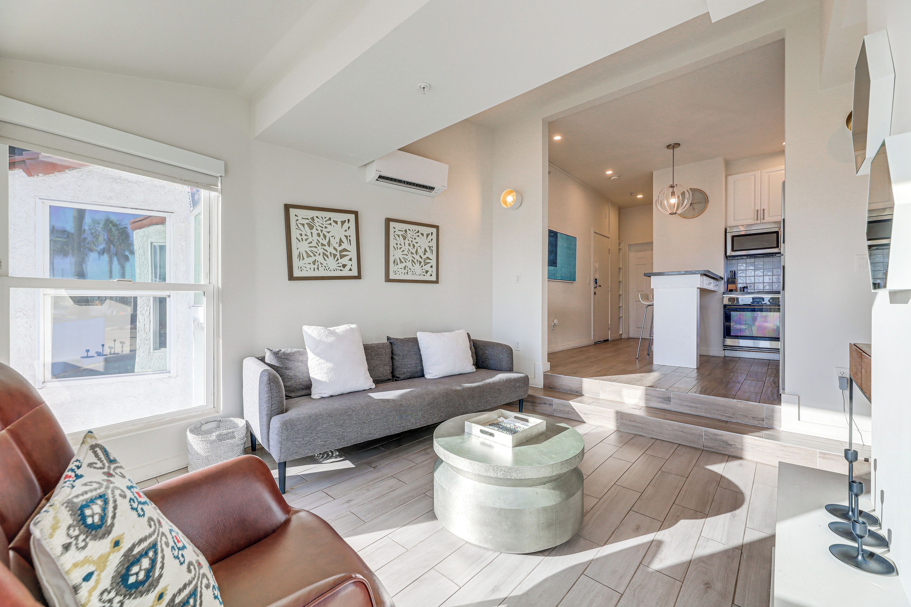 A modern living room with a grey sofa, a coffee table, and a view of the kitchen.
