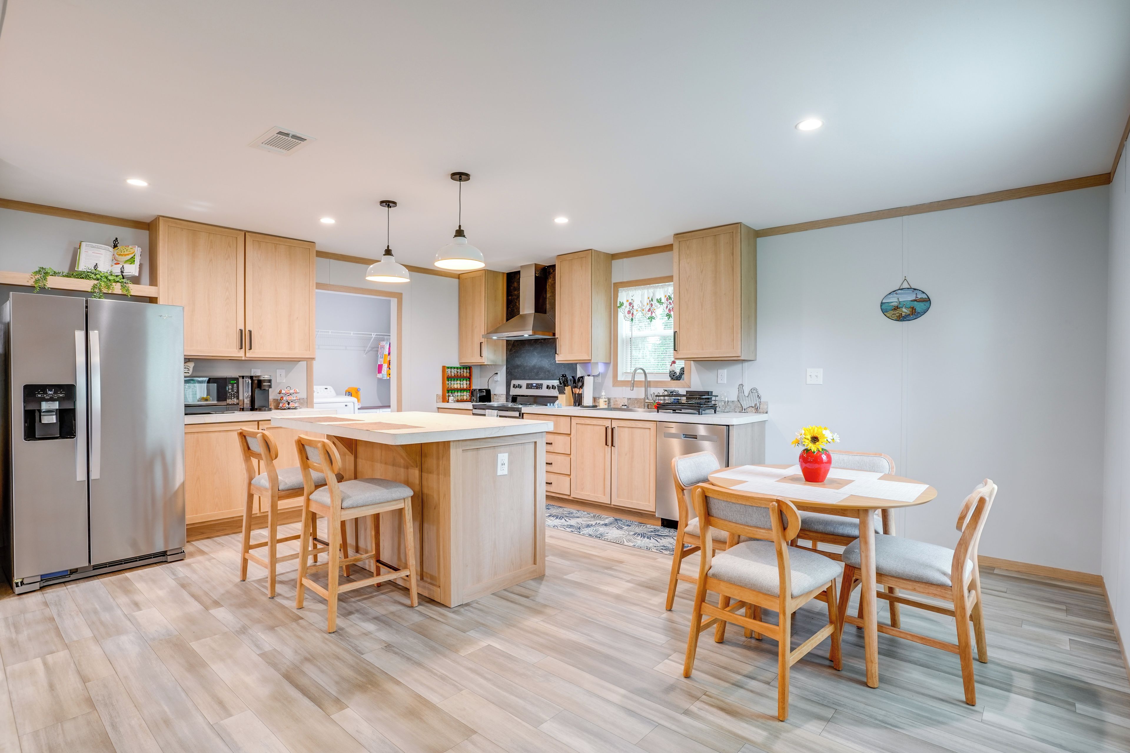 Una cocina moderna con armarios de madera, una isla central y un comedor con sillas.