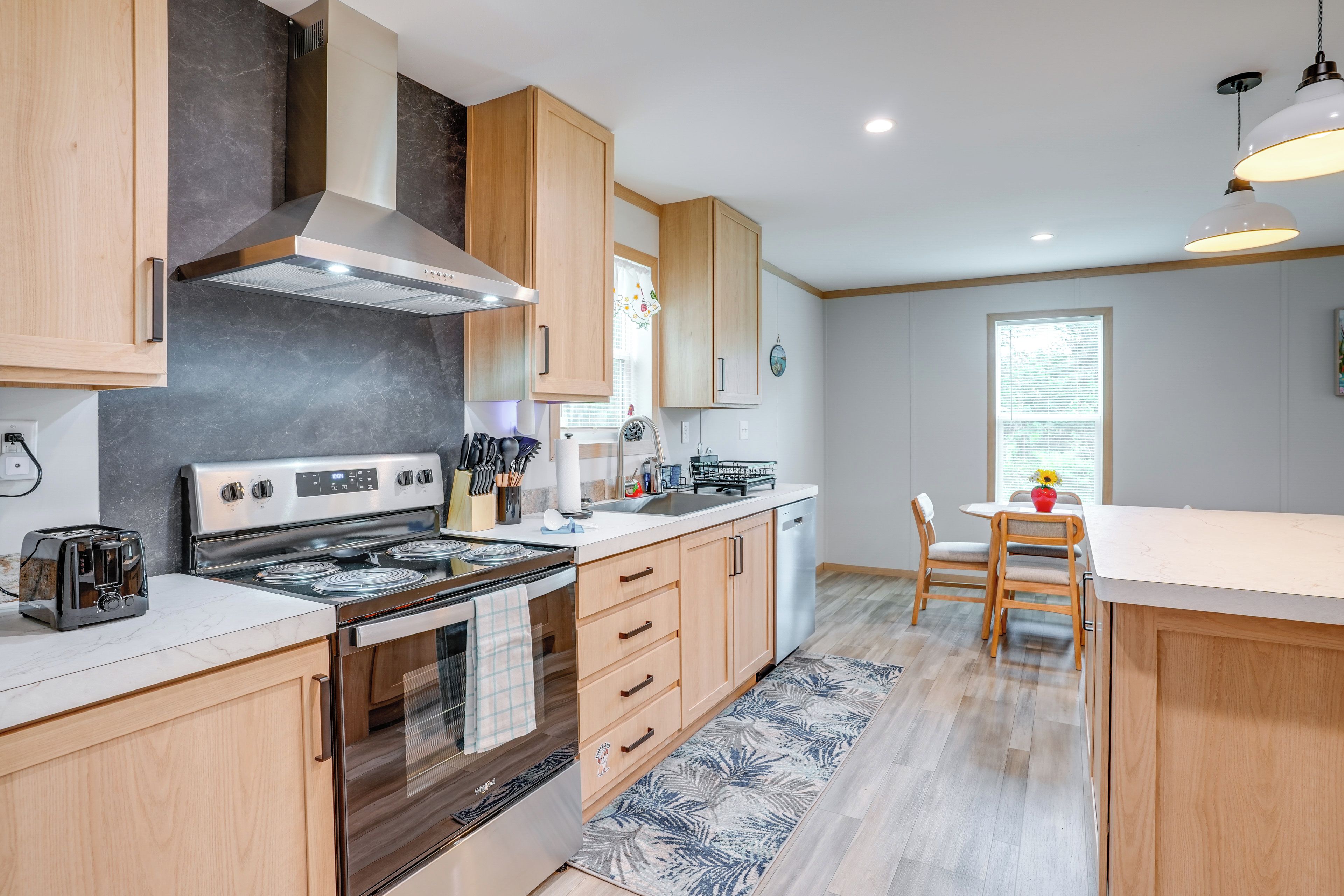 Una cocina moderna con estufa, horno y comedor con mesa y sillas.