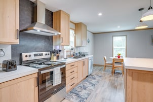 Una cocina moderna con estufa, horno y comedor con mesa y sillas.