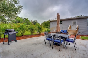 An outdoor patio with a barbecue grill, a table with chairs, and a covered area with an umbrella. - Easy I-4 Access: Central Florida Home w/ Fire Pit (Plant City)