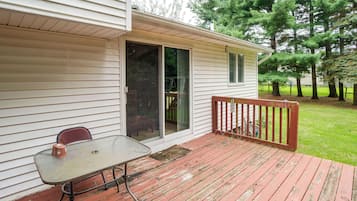 Un patio techado con mesa y sillas, una puerta corrediza de vidrio y una terraza de madera.