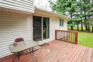 A covered patio with a table and chairs, a sliding glass door, and a wooden deck.