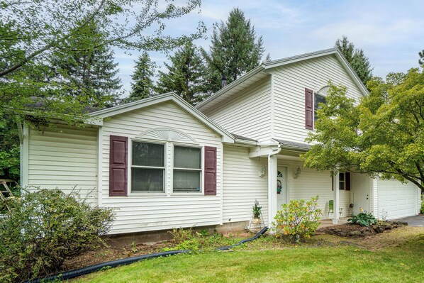 A two-story house with a front porch, a garage, and a well-maintained lawn.