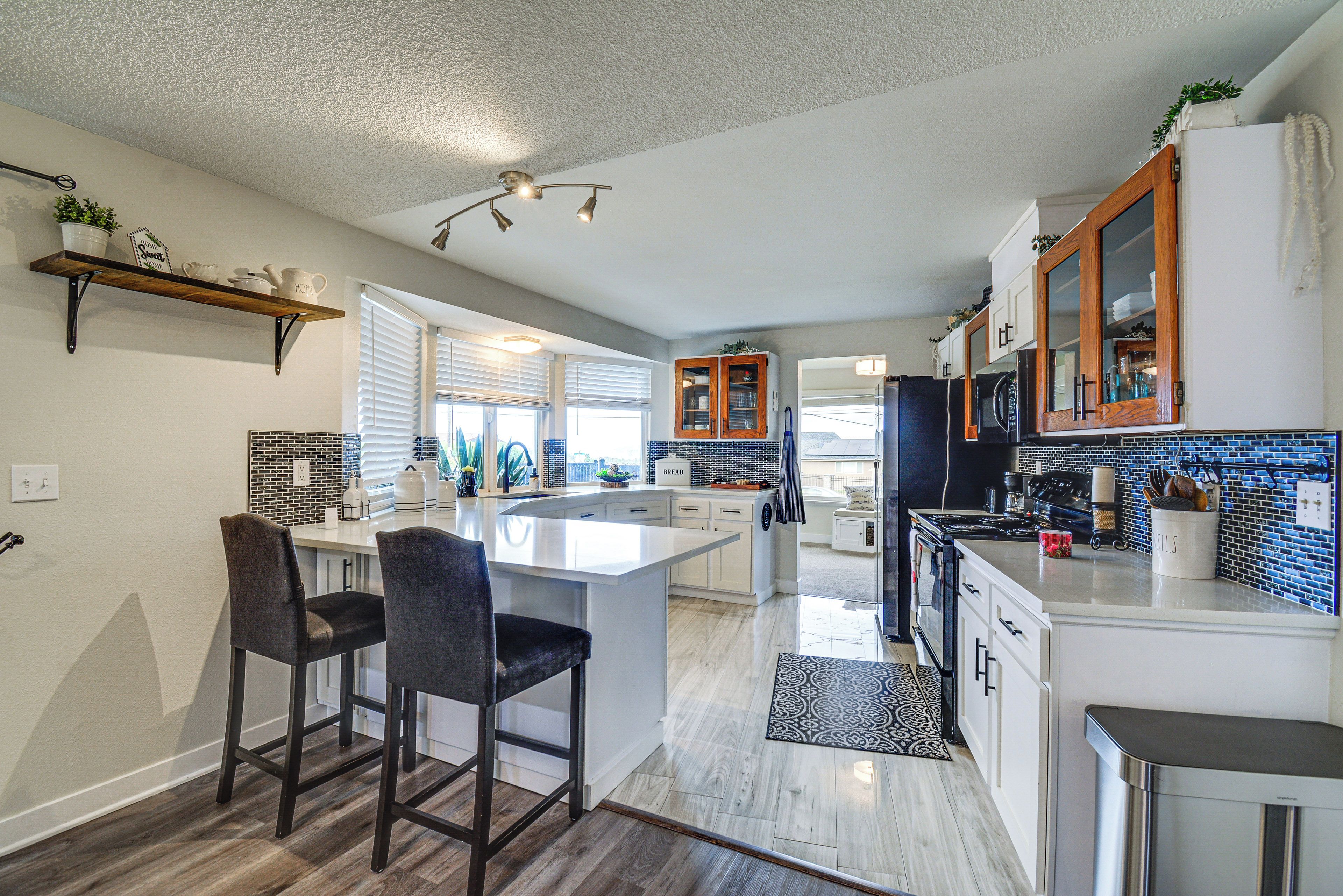 A modern kitchen with a central island, bar stools, a built-in oven, and a microwave.