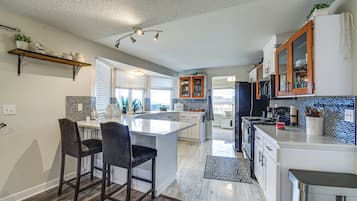A modern kitchen with a central island, bar stools, a built-in oven, and a microwave.