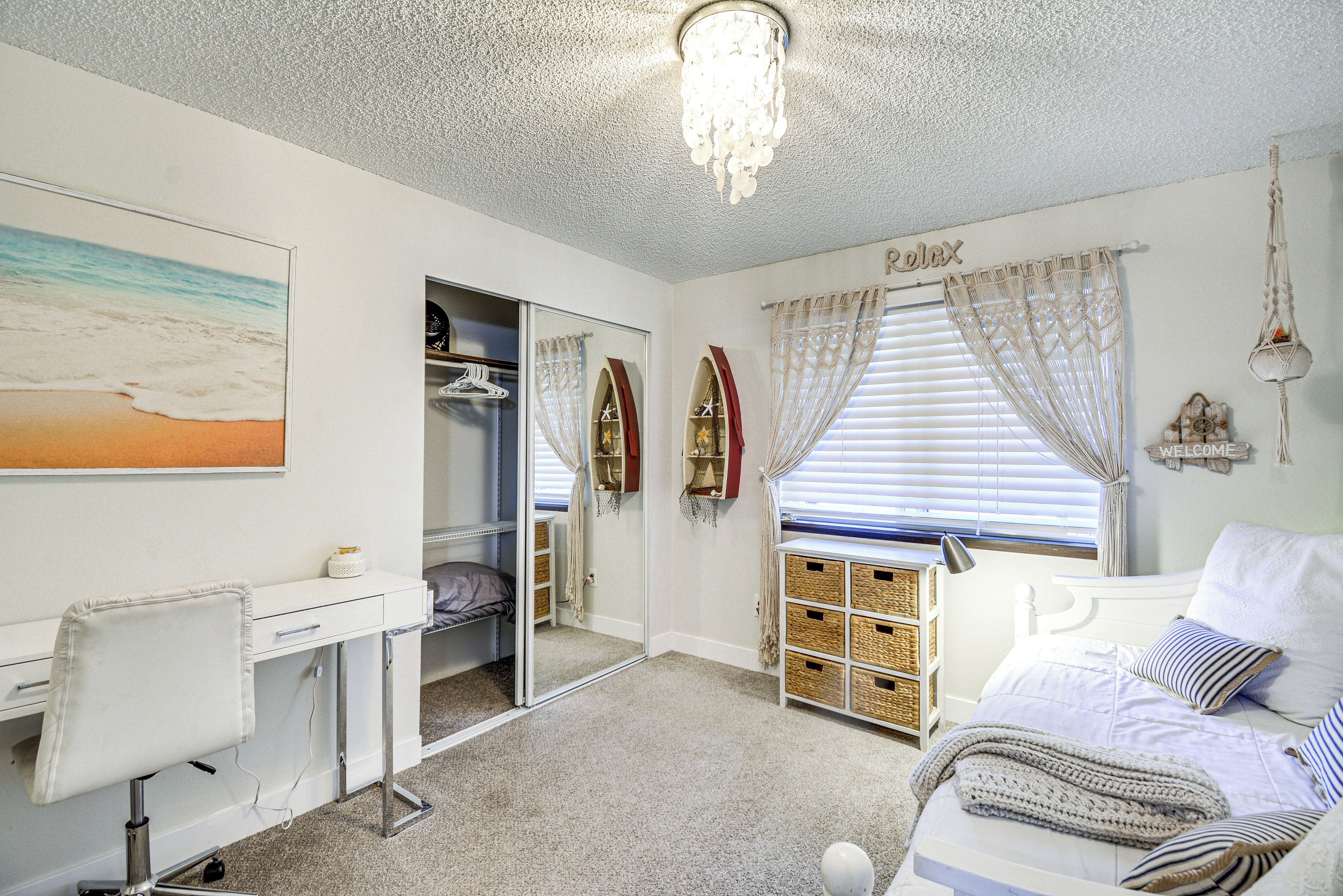 A bedroom with a bed, a desk, a wardrobe, and a window with curtains.
