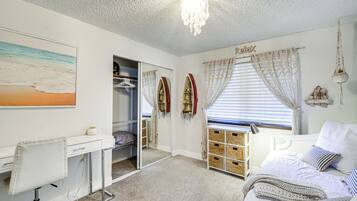 A bedroom with a bed, a desk, a wardrobe, and a window with curtains.